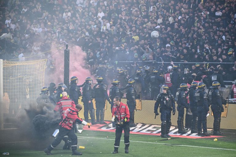 Des supporters nantais quittent la pelouse sous la surveillance des forces de l'ordre après les incidents