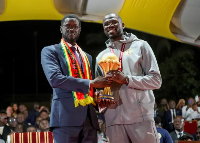Le président sénégalais Bassirou Diomaye Faye et le capitaine Khalidou Koulibaly avec le trophée de la CAN