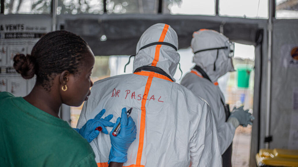 Un agent d'hygiène inscrit le nom d'un médecin au dos de sa combinaison de protection individuelle avant d'entrer dans un centre de traitement Ebola à Bunia, dans l'est de la République démocratique du Congo
