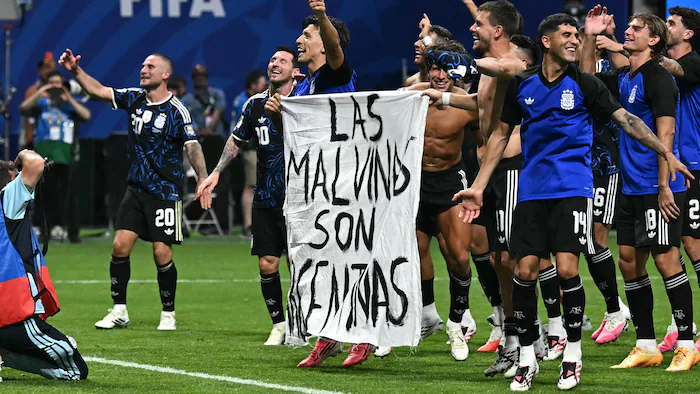 Joueurs argentins tenant une banderole 'Les Malouines sont argentines' après le match