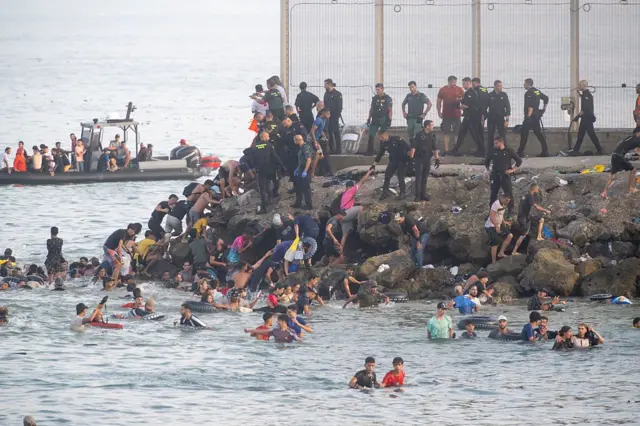 Des migrants traversant la frontière vers Ceuta, illustrant les défis migratoires actuels.
